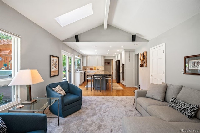 living room featuring recessed lighting, a skylight, beamed ceiling, light wood-style floors, and light colored carpet