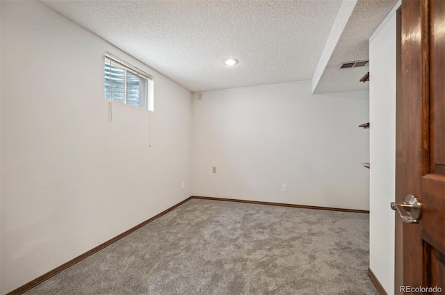 basement featuring a textured ceiling, carpet, and baseboards