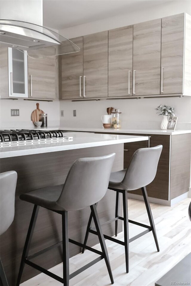 3615 Navajo St, Denver, CO 80211 - kitchen featuring a breakfast bar, modern cabinets, light countertops, and glass insert cabinets