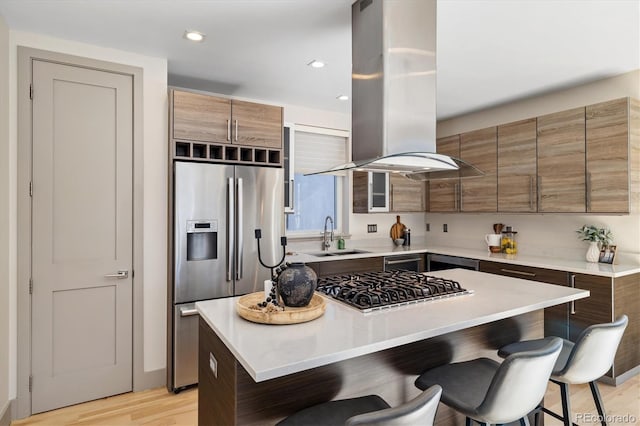 3615 Navajo St, Denver, CO 80211 - kitchen featuring appliances with stainless steel finishes, island range hood, a sink, a kitchen breakfast bar, and a center island
