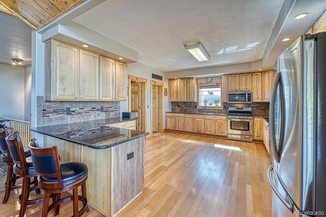 2680 Wild Bill Blvd, Westcliffe, CO 81252 - kitchen with stainless steel appliances, a peninsula, a textured ceiling, tasteful backsplash, and a breakfast bar