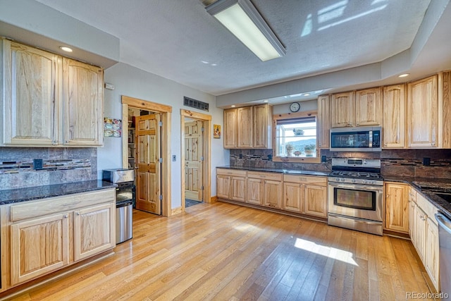 2680 Wild Bill Blvd, Westcliffe, CO 81252 - kitchen with appliances with stainless steel finishes, light brown cabinetry, light wood-type flooring, tasteful backsplash, and dark stone counters