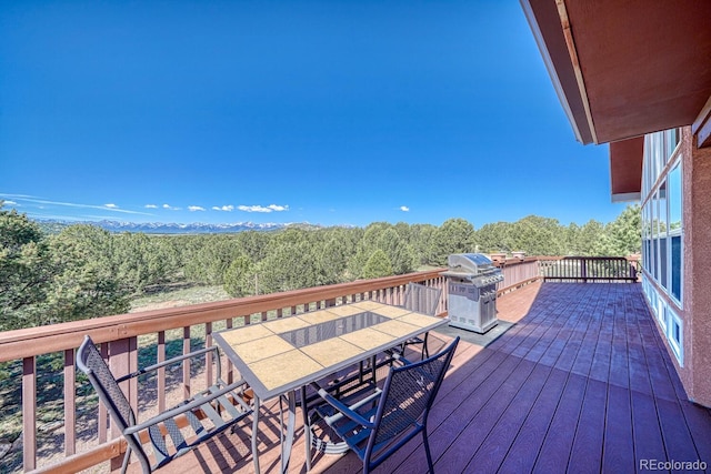 2680 Wild Bill Blvd, Westcliffe, CO 81252 - wooden terrace featuring outdoor dining space, a grill, and a wooded view