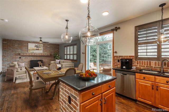 kitchen featuring dishwasher, dark countertops, dark wood-style floors, a fireplace, and a sink