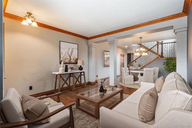 living area featuring an inviting chandelier, decorative columns, ornamental molding, and wood finished floors