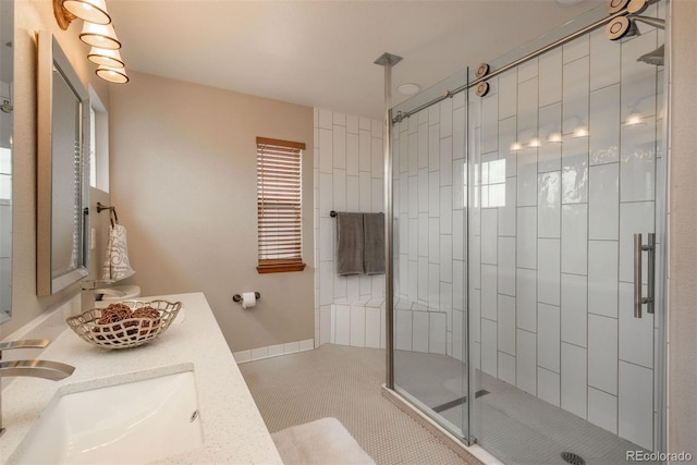 full bath with double vanity, baseboards, tile patterned floors, a shower stall, and a sink