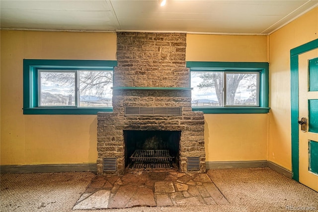 unfurnished living room featuring a stone fireplace and carpet