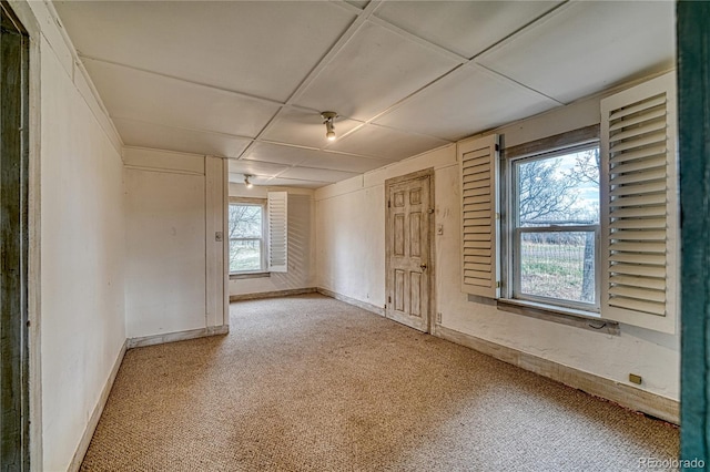 carpeted empty room with a drop ceiling