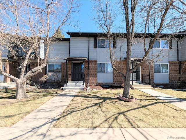 view of property featuring brick siding and a front yard