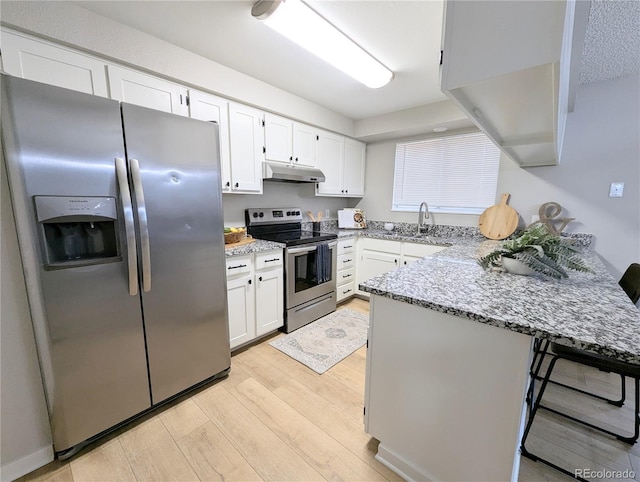 kitchen featuring a peninsula, a sink, stainless steel appliances, under cabinet range hood, and white cabinetry