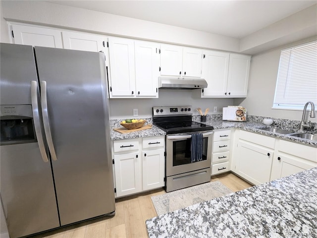 kitchen with under cabinet range hood, white cabinets, appliances with stainless steel finishes, and a sink