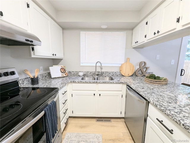 kitchen with light wood-type flooring, a sink, under cabinet range hood, stainless steel appliances, and white cabinets