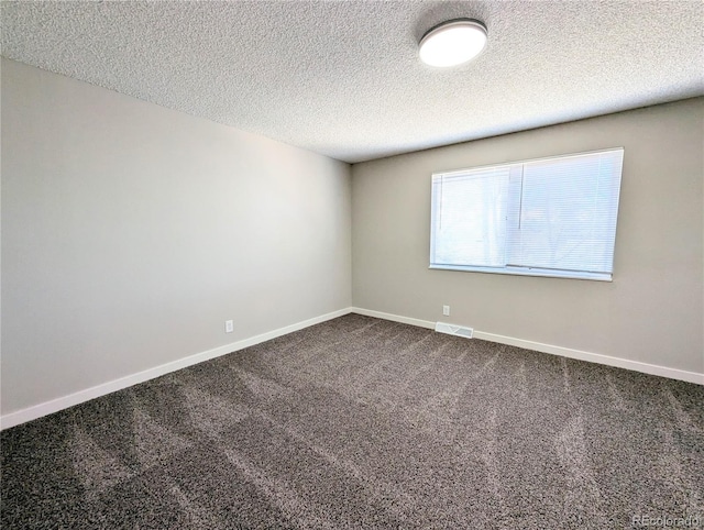 empty room featuring dark colored carpet, visible vents, baseboards, and a textured ceiling