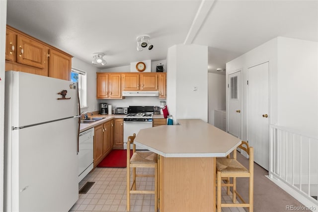 165 Coyotero Trl, Hartsel, CO 80449 - kitchen featuring white appliances, under cabinet range hood, light countertops, a breakfast bar, and a center island
