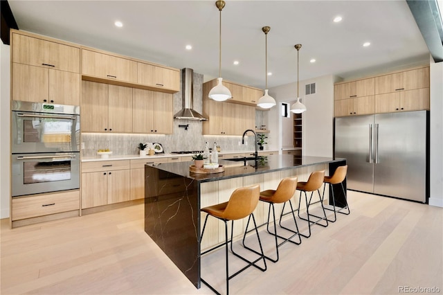 1601 S Columbine St, Denver, CO 80210 - kitchen with appliances with stainless steel finishes, light brown cabinetry, wall chimney exhaust hood, a sink, and modern cabinets