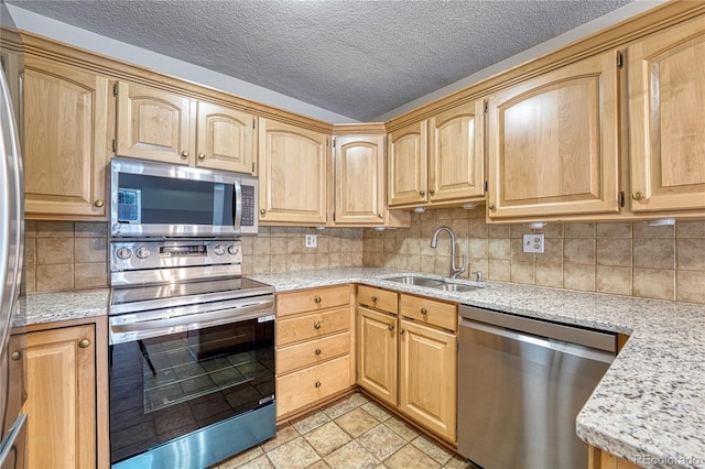 kitchen with sink, appliances with stainless steel finishes, tasteful backsplash, light stone countertops, and a textured ceiling