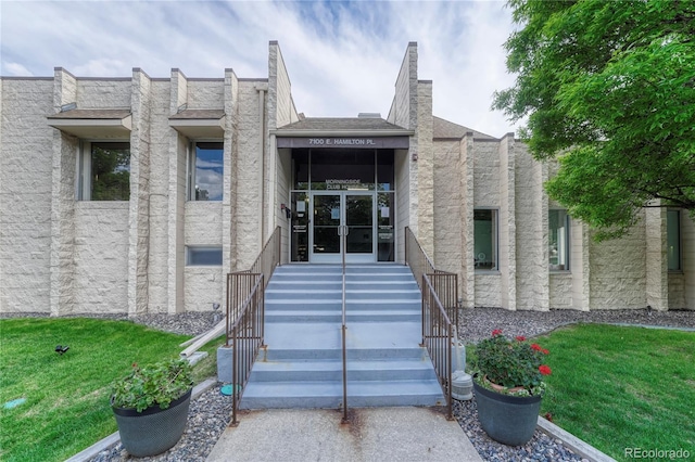 view of exterior entry featuring a lawn