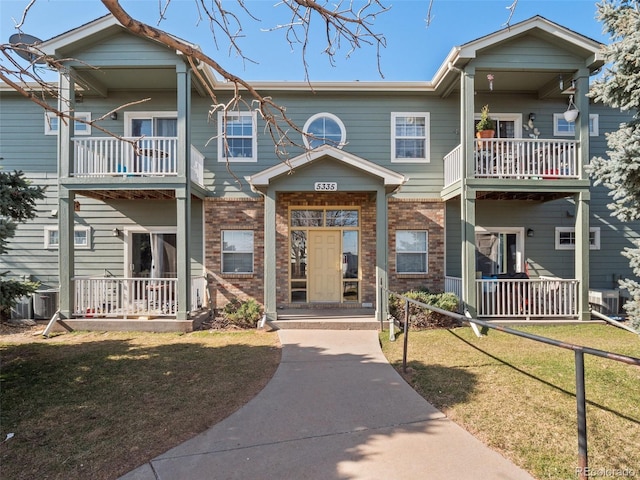 view of front facade featuring brick siding, covered porch, and a front lawn