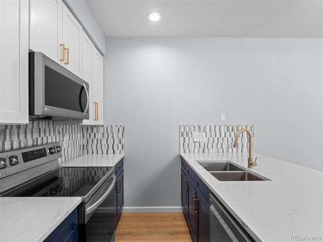 kitchen with a sink, decorative backsplash, light stone counters, and stainless steel appliances