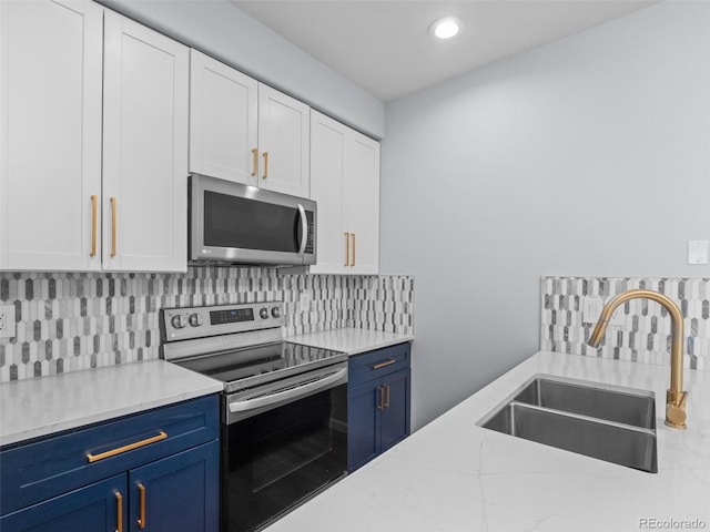 kitchen featuring a sink, stainless steel appliances, white cabinets, blue cabinets, and tasteful backsplash