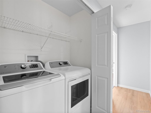 laundry room featuring baseboards, light wood-style floors, washing machine and dryer, and laundry area