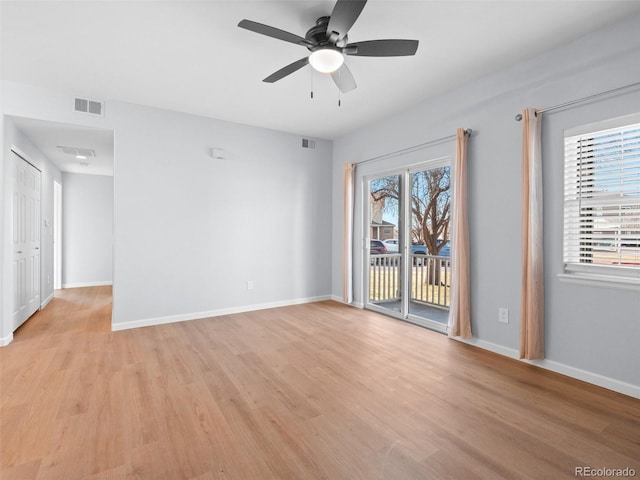 unfurnished room with light wood-type flooring, visible vents, and baseboards