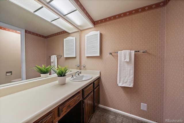 bathroom with wallpapered walls, visible vents, vanity, and baseboards