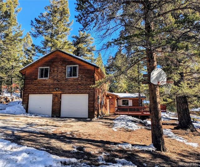 view of snow covered exterior with a garage and a deck