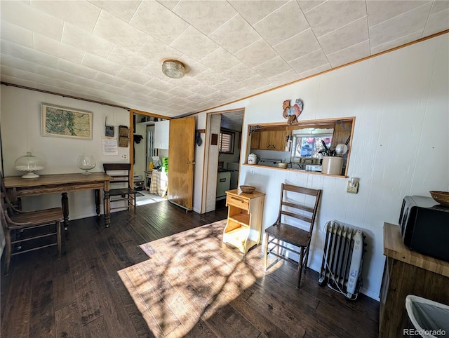 dining area featuring radiator heating unit, dark hardwood / wood-style flooring, lofted ceiling, and crown molding