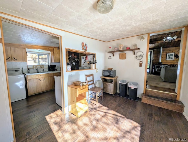 kitchen with washer / clothes dryer, sink, dark hardwood / wood-style flooring, and a wood stove