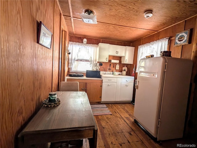 kitchen with wooden walls, white cabinets, wooden ceiling, and white refrigerator