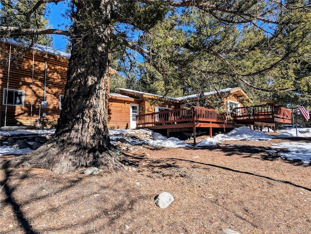 snow covered back of property with a wooden deck