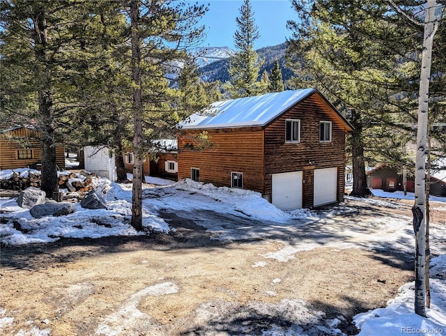 snow covered property with a mountain view and a garage