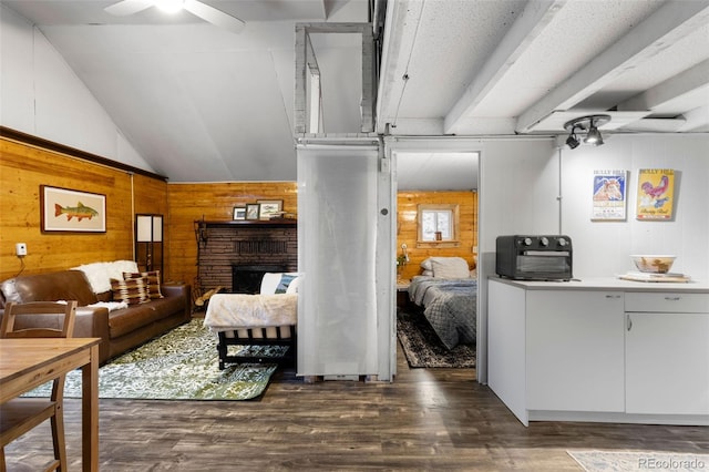 living room featuring dark hardwood / wood-style floors, wood walls, a brick fireplace, lofted ceiling, and ceiling fan