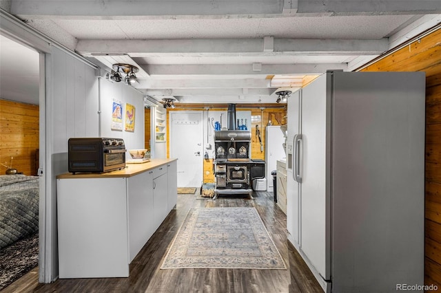 kitchen featuring dark hardwood / wood-style flooring, white cabinets, wood walls, white refrigerator with ice dispenser, and beam ceiling