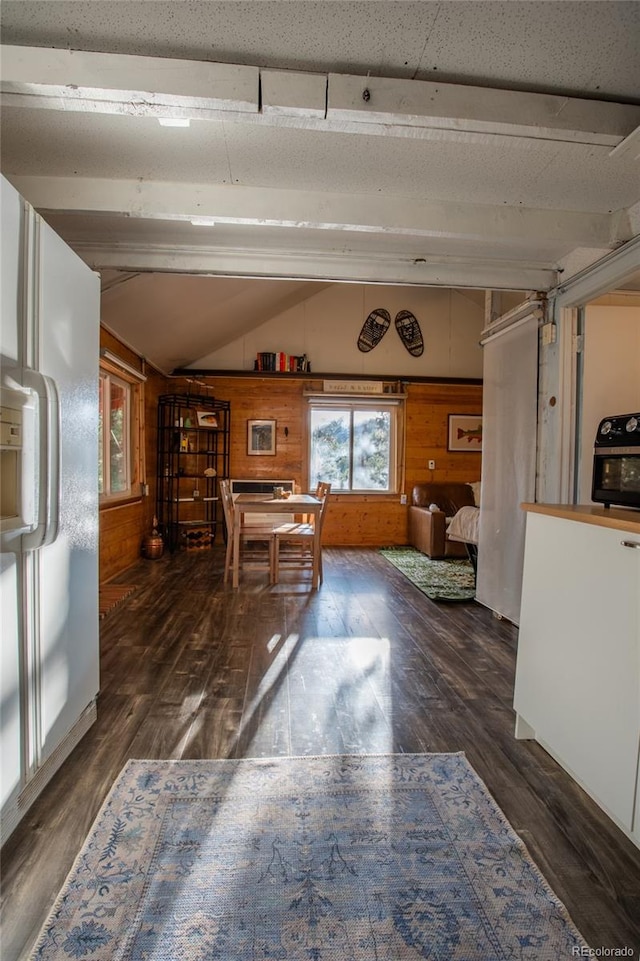 dining room with dark hardwood / wood-style floors, wooden walls, and lofted ceiling