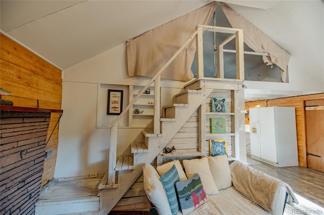 staircase with wood walls, hardwood / wood-style floors, and vaulted ceiling