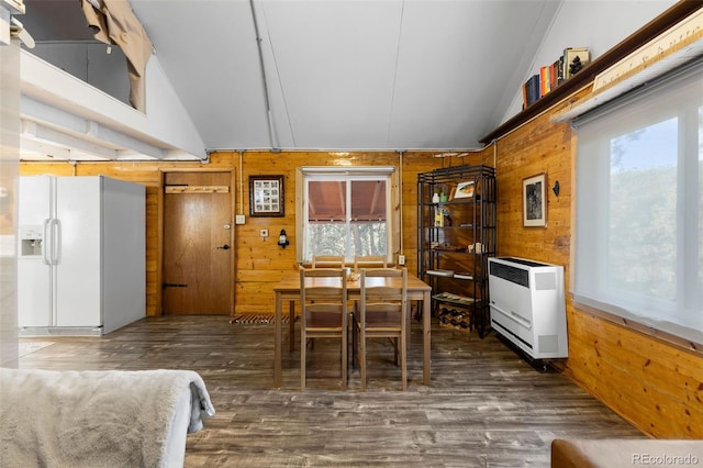 dining space featuring wood walls and vaulted ceiling