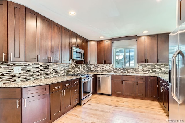 1733 S Gilpin St, Denver, CO 80210 - kitchen with appliances with stainless steel finishes, backsplash, light wood-style floors, light stone counters, and recessed lighting