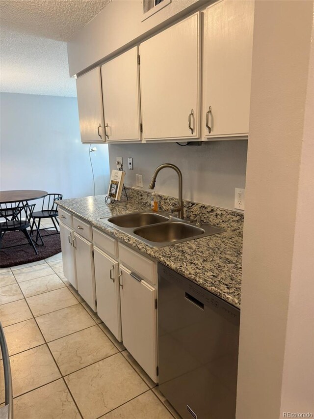 kitchen featuring stainless steel dishwasher, a sink, a textured ceiling, white cabinets, and light tile patterned flooring
