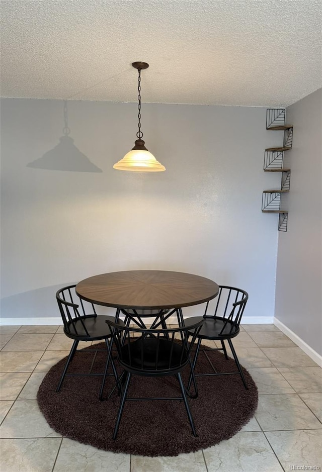 dining room with tile patterned flooring, baseboards, and a textured ceiling