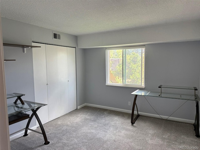 unfurnished bedroom featuring carpet flooring, a textured ceiling, a closet, and baseboards