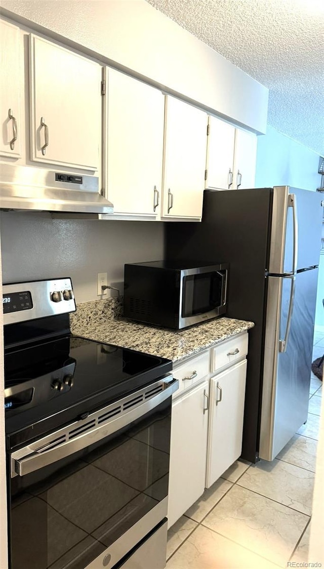 kitchen with under cabinet range hood, stainless steel appliances, white cabinetry, a textured ceiling, and light stone countertops
