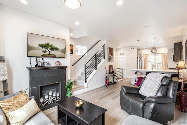 3449 W 63rd Pl, Denver, CO 80221 - living area with a fireplace, light wood-style flooring, baseboards, visible vents, and stairway