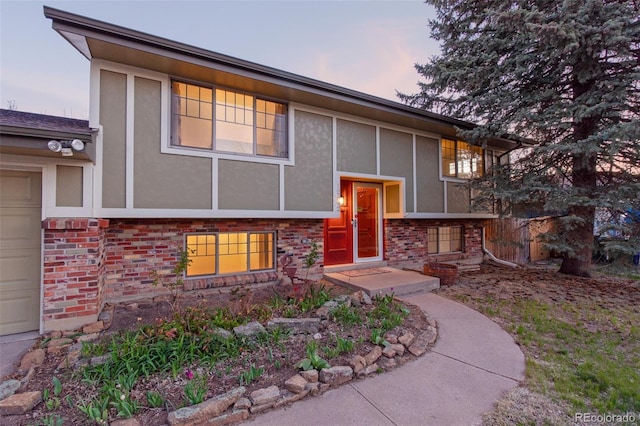 bi-level home featuring stucco siding and brick siding