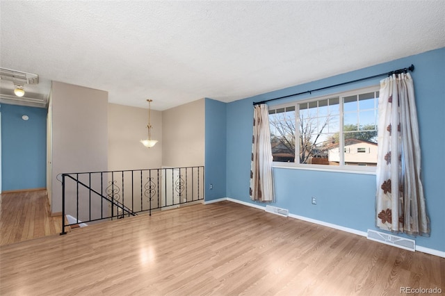 spare room featuring baseboards, visible vents, and wood finished floors