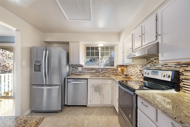 kitchen with under cabinet range hood, a sink, white cabinetry, tasteful backsplash, and appliances with stainless steel finishes