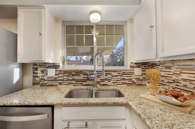 kitchen with a sink, stainless steel dishwasher, tasteful backsplash, and white cabinetry