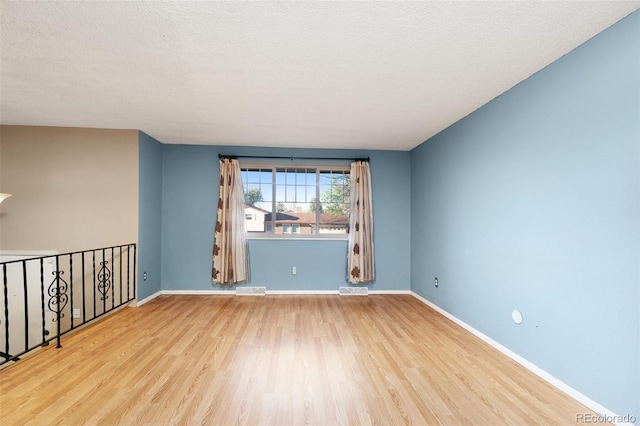 empty room with visible vents, wood finished floors, and baseboards