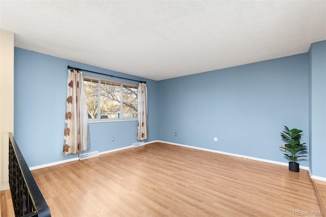 unfurnished room with visible vents, wood finished floors, and baseboards